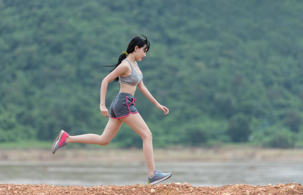 woman-running-across-dirt-field-next-to-forest